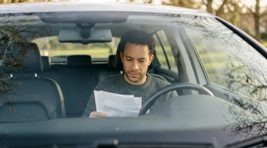 Conducteur assis dans un vehicule examine des documents d'assurance